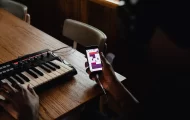 Person holding a phone connected to a digital piano