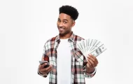a man holding a smartphone and cash