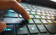 A computer keyboard with a finger on a key
